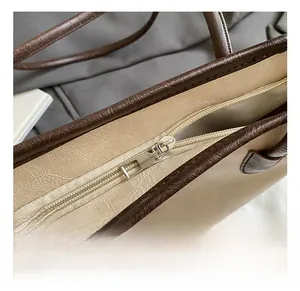 Detail of premium silver metal zipper and contrast trim on apricot faux leather tote