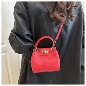 Detail of red lychee pattern leather handbag with gold metal lock and shoulder strap