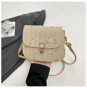 Detail of straw woven bag with floral embroidery and golden horseshoe clasp