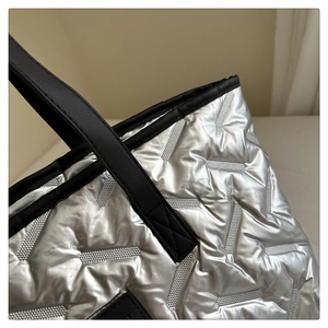 Detail of silver quilted tote bag showing metallic texture and geometric stitching