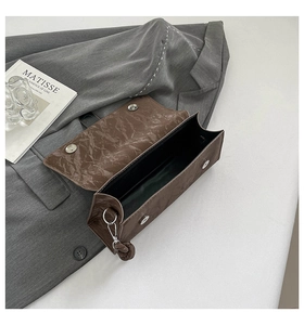Detail of brown pleated PU leather shoulder bag with magnetic snaps and silver D-rings