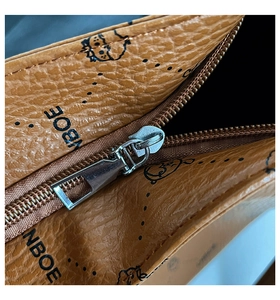 Macro shot of brown pebble grain leather handbag with silver zipper and cartoon print