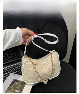 Détail du sac beige tissé avec chaîne dorée ornée de perles et de charms coquillages