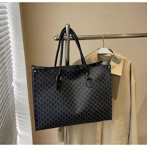 Detail view of large grey tote bag with repetitive M print and gold rivet hardware