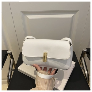 Detail of white patent leather shoulder bag with a polished gold rectangular metal buckle