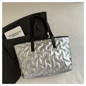 Detailed view of silver quilted tote bag with metallic finish and long black handles