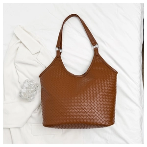 Detail of brown woven tote bag showing intricate texture and silver metal buckle