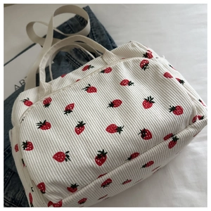 Détail de la texture velours côtelé et motif fraise sur un grand sac déjeuner
