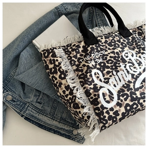 Detail of leopard print tote bag with white fringe and black canvas shoulder handles