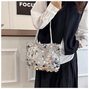 Detail of silver sequin shoulder bag with pearly bow pendant and glossy texture