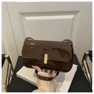 Close-up of glossy brown patent leather shoulder bag with elegant gold metal clasp
