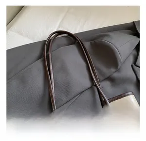 Detail showing high-quality cream leather texture and dark brown shoulder strap handles