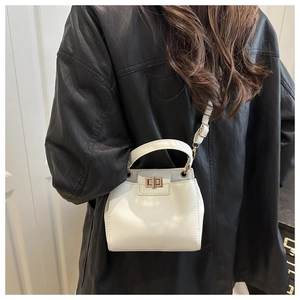 Detailed view of white lychee pattern crossbody bag with gold twist lock on black leather jacket