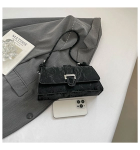 Detail of black marble textured shoulder bag with silver buckle and phone for size reference