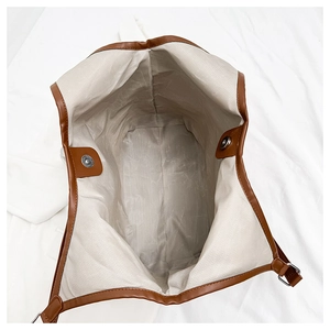 Detailed interior of tote bag with beige herringbone lining and magnetic snap closure