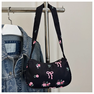 Detail of black underarm bag featuring pink rose and bow prints with secure zip closure