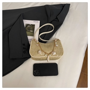 Détail d'un sac porté épaule en paille avec perles, coquillages et breloque étoile de mer