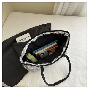 Detail showing high-capacity interior of silver quilted tote bag with tablet and daily items