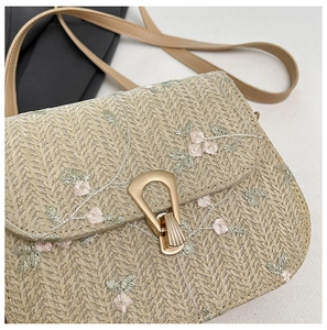 Detail of floral embroidery and textured straw weaving on a compact crossbody bag