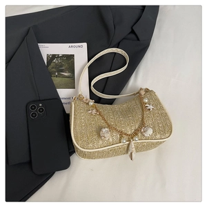 Détail du sac à bandoulière en paille avec breloques perles et coquillages sur veston