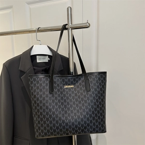 Large black tote bag with gray M letter print and gold logo on metal display stand