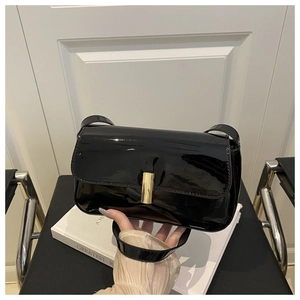 Detail of high-gloss black patent leather shoulder bag with gold rectangular metal buckle