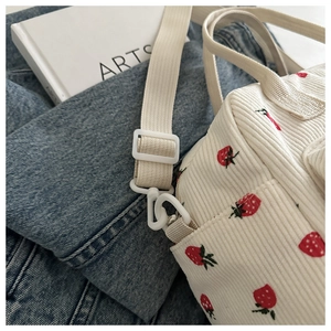 Détail du sac en velours côtelé blanc avec broderie fraise et sangle réglable