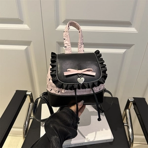 Sac à dos en cuir noir et rose avec nœud et pendentif cœur sur fond blanc épuré