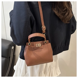 Brown litchi leather trapezoid handbag with gold twist lock worn by a model
