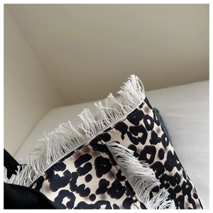 Detail of leopard print tote bag with thick white fringe accents and black strap