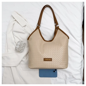 Top view of woven beige tote bag with brown trim and phone for size reference