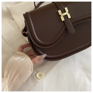 Close-up of matte dark brown leather crossbody bag with iconic gold H-shaped hardware buckle