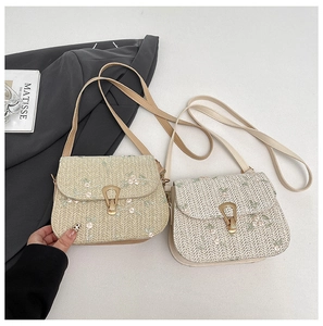 Detail of straw woven bags with floral embroidery and gold metal lock on a neutral fabric