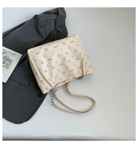 Detailed macro view of cream leather shoulder bag with bear pattern and silver chain strap