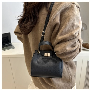 Detail of black litchi pattern bag showing golden rectangular twist lock and top handle