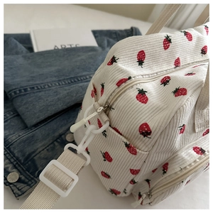 Détail du sac en velours côtelé à motif fraise avec poignée crème et bandoulière