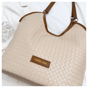 Detail of woven texture and leather logo tag on a large beige and brown tote bag