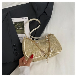 Détail du sac en paille avec chaîne perles et coquillages sur tissu blanc texturé