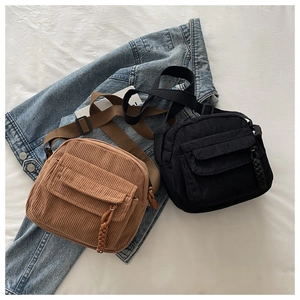 Detail view of corduroy crossbody bags in brown and black with woven zipper pulls