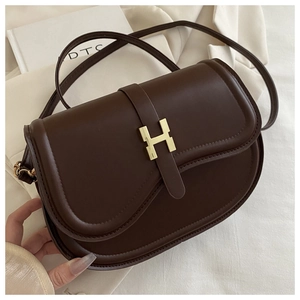 Close-up of the vintage dark brown saddle bag with a golden H-shaped metal buckle detail