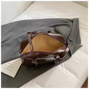 Detail view of the spacious yellow fabric lining and silver zipper of a dark brown glossy bag