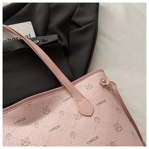 Detailed view of pink tote bag with pebble leather texture and cartoon character prints