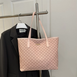 Pink tote bag with repetitive M print and gold metal logo on a minimalist hanger