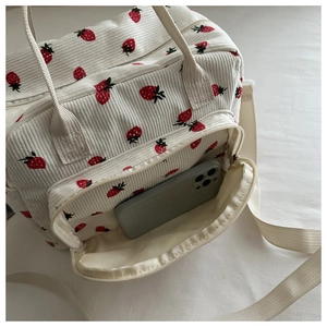 Détail de la poche avant du sac à lunch en velours fraise avec un téléphone