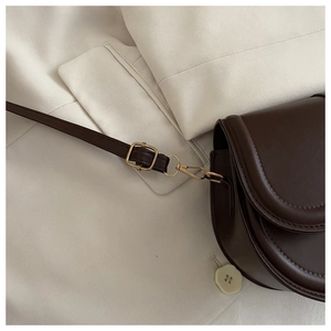 Close-up of dark brown PU leather crossbody bag with golden hardware and neat stitching