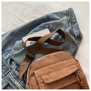 Detail of brown corduroy crossbody bag with zipper and flap pocket on denim jacket
