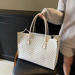 White minimalist tote bag with grey M-letter print and double handles on a black chair