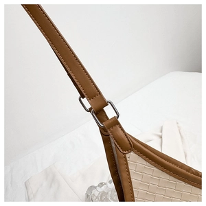 Detail of woven faux leather texture and silver buckle on a bicolor shoulder bag