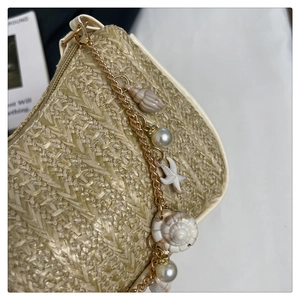 Détail du sac en paille avec chaîne dorée ornée de coquillages et de perles