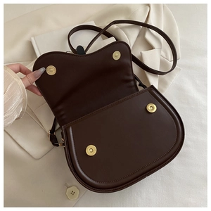 Detailed close-up of dark brown leather saddle bag with magnetic gold metal buckles
